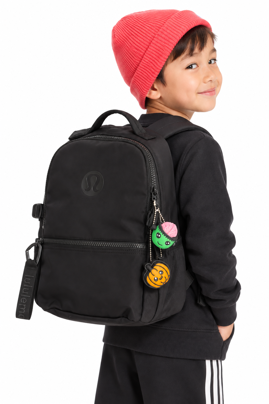 Child wearing a black backpack displaying Pumpkin Pop and another clicker; backpack and other clicker not included