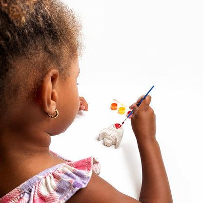 Child painting the rocket plaster figure