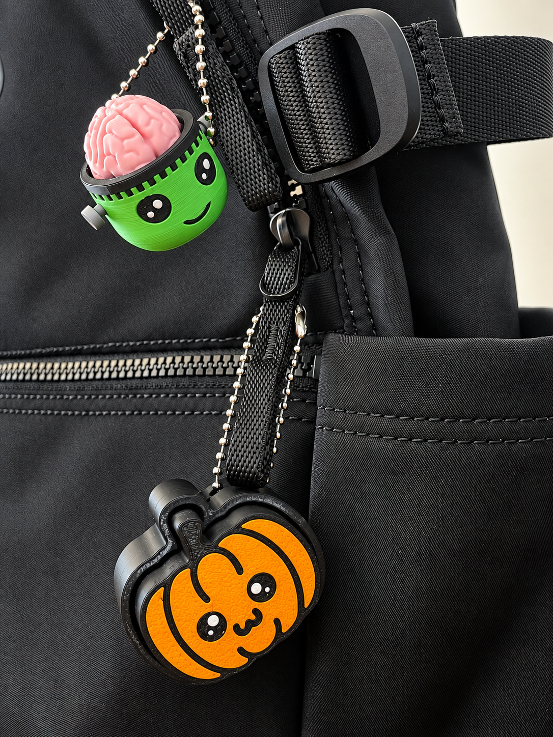 Frankie and Pumpkin Pop clickers attached to a black bag; bag and other clicker not included