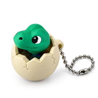 Green dinosaur clicker peeking out of a cream cracked egg with a silver ball chain