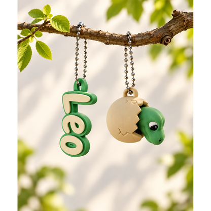 Dinosaur clicker and example Leo name keychain hanging together from a branch