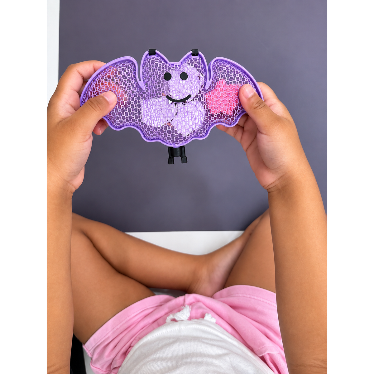 Hands holding the purple bat-shaped Halloween chalk case