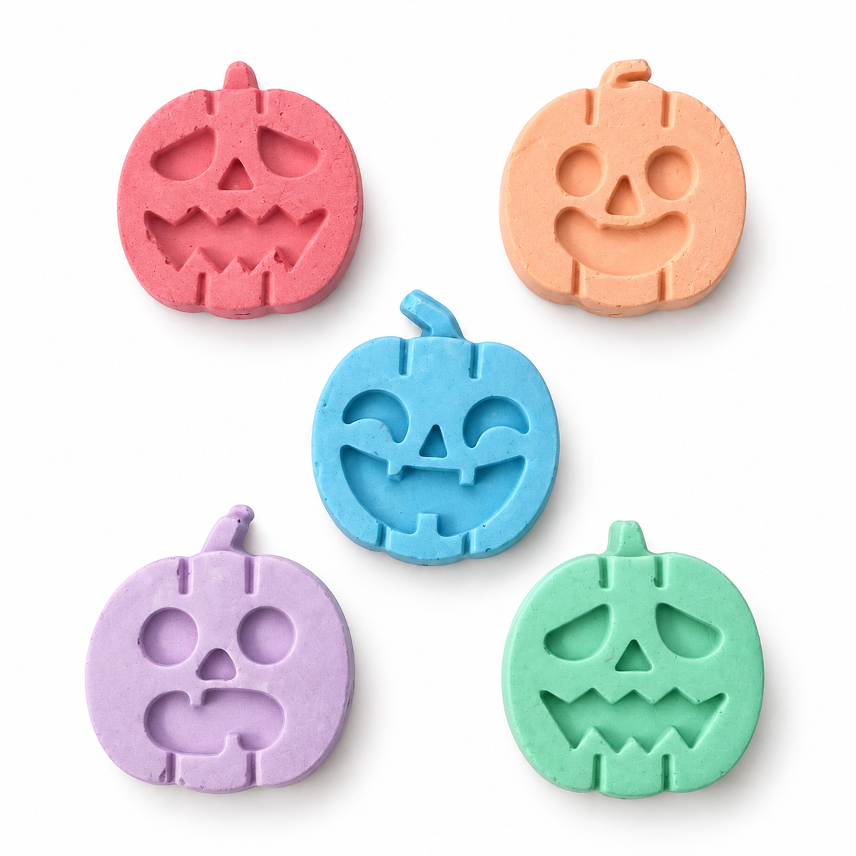 Five colorful pumpkin-shaped chalk pieces arranged on white