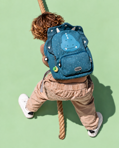 Child wearing a dinosaur backpack with the name-and-dino keychains; backpack not included