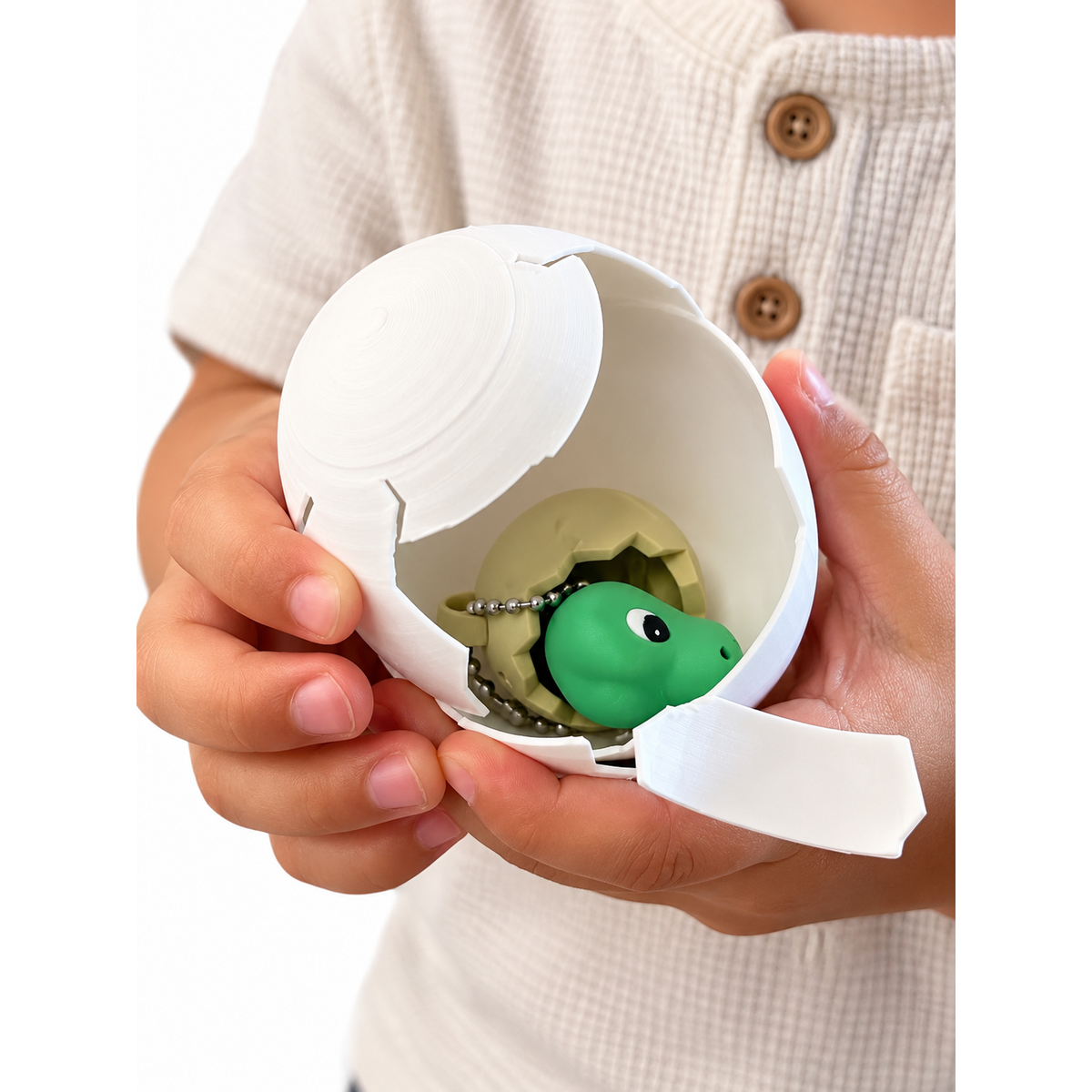 Hands opening the included white outer egg to reveal the dinosaur clicker