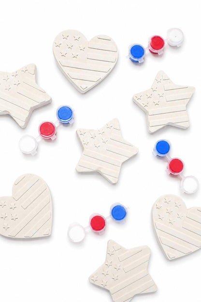 Styled arrangement of multiple unpainted patriotic star and heart shapes with paint pots